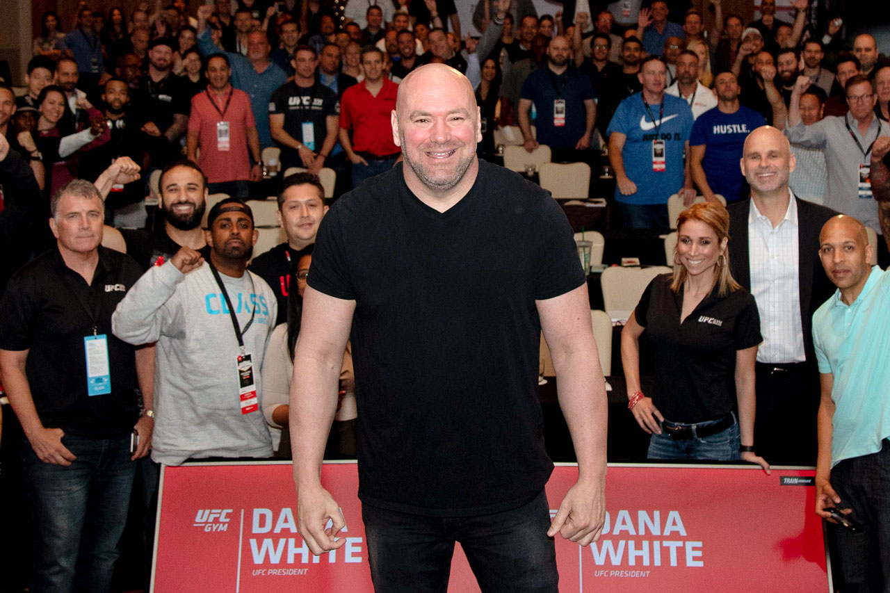 Dana White standing in front for a photo with people in the background